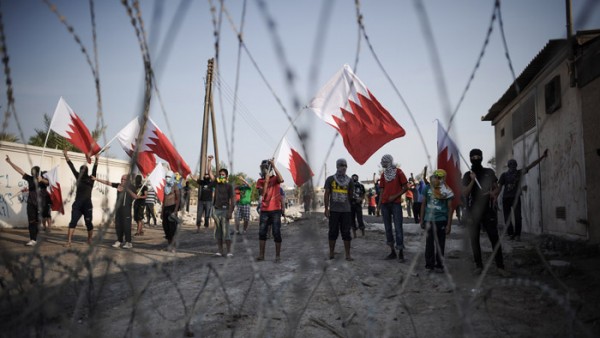 TOPSHOTS Bahraini protestors wave their ...TOPSHOTS Bahraini protestors wave their national flag as they stand behind barbed wire placed by riot police during demonstration against the ruling regime in the village of Shakhora, west of Manama, on August 14, 2013.. Bahraini police headed off a protest against Gulf kingdom's Sunni rulers that the Shiite-led opposition activists called for near the US embassy in defiance of a ban. The police deployment prevented protesters from reaching the spot designated by the Bahrain Rebellion Movement, Tamarod, for the main rally outside the US embassy in the capital Manama. AFP PHOTO/MOHAMMED AL-SHAIKHMOHAMMED AL-SHAIKH/AFP/Getty Images