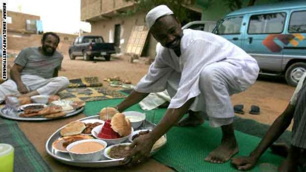 A Sudanese man lays a tray of food as Mu