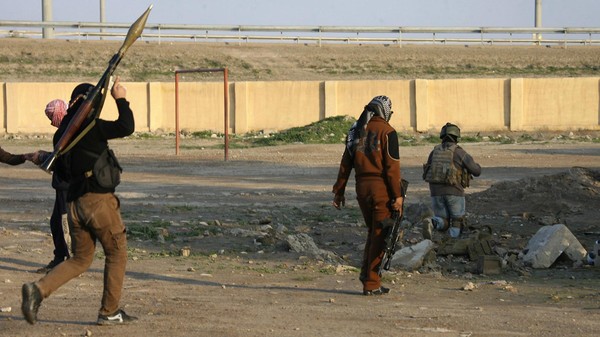 Masked Sunni Muslim gunmen take up positions with their weapons during a patrol in the city of Falluja