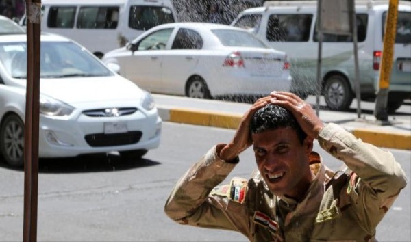 جندي بصراوي يرشق الماء على جسمه بسبب ارتفاع درجات الحرارة في مدينة البصرة 