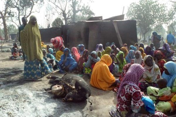 © اف ب | نساء يجلسن امام بقرة نافقة بعد هجوم لبوكو حرام على قرية دالوري قرب مايدوغوري 31 يناير 2016