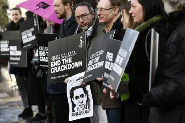 متظاهرون يحملون صورة المدون السعودي رائف بدوي خارج السفارة السعودية في لندن يوم الثامن من يناير كانون الثاني 2016. تصوير: ستيفان ورموث - رويترز. 