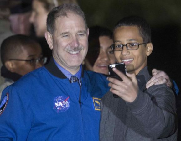 Ahmed Mohamed, 14, the Texas teenager who was arrested after bringing a homemade electronic clock to school, takes a selfie with John M. Grunsfeld (L), Associate Administrator for the Science Mission Directorate, during the second White House Astronomy Night on the South Lawn of the White House in Washington in this October 19, 2015 file photo. The family of a Texas teenager, arrested for bringing a homemade clock to school that was mistaken for a bomb, demanded $15 million in damages and an apology from the city of Irving and its schools to avoid a lawsuit, lawyers said on November 23, 2015.        REUTERS/Joshua Roberts/Files