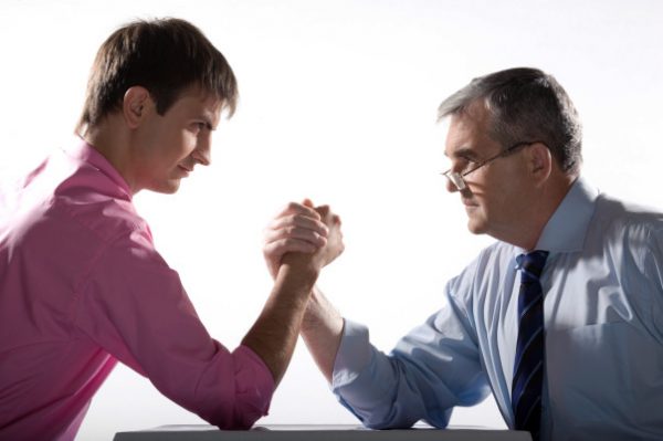 Profiles of two partners looking at each other while arm wrestling