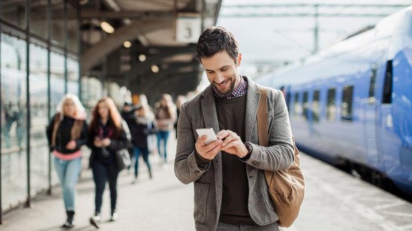 Businessman using mobile phone at train station