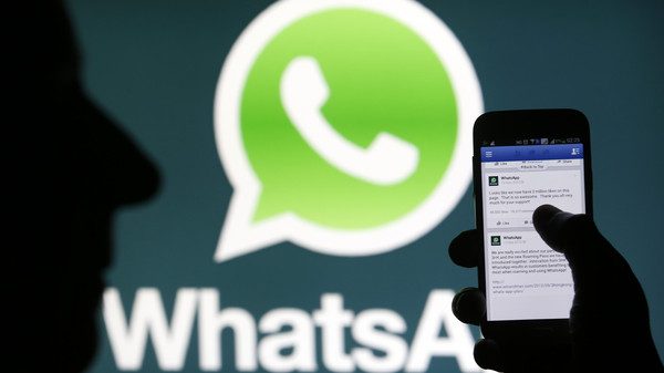 A Whatsapp App logo is seen behind a Samsung Galaxy S4 phone that is logged on to Facebook in the central Bosnian town of Zenica