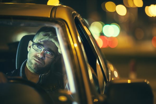 Caucasian white man wearing glasses in his car. Concept for negative feelings