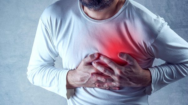 Severe heartache, man suffering from chest pain, having heart attack or painful cramps, pressing on chest with painful expression.