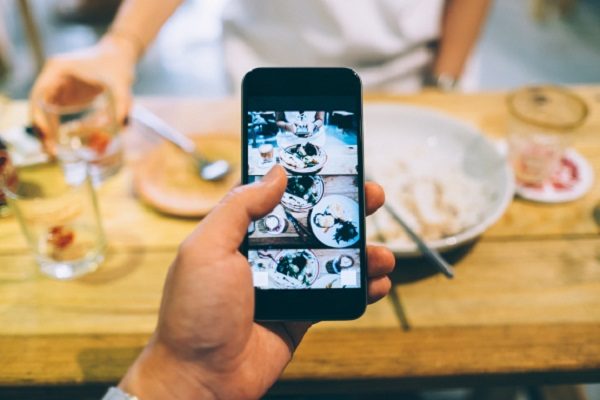 Capturing the snapshots of an enjoyable meal with friends by smartphone in a cafe.